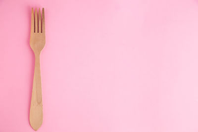 Directly above shot of wooden fork over pink background