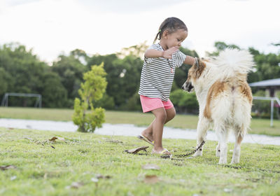 Portrait of young woman with dog running on field