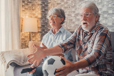 Side view of man holding soccer ball at home