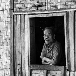 Portrait of man sitting against window of building