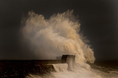 Sea waves splashing on shore against sky