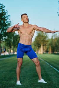 Portrait of shirtless man exercising on field