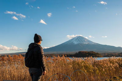 Rear view of man standing on land against sky