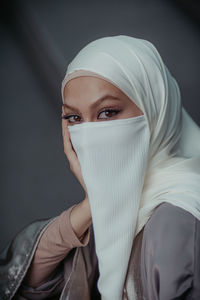 Close up portrait of veiled muslim woman wearing white hijab and niqab from high angle.