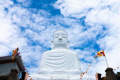 Low angle view of buddha statue against sky