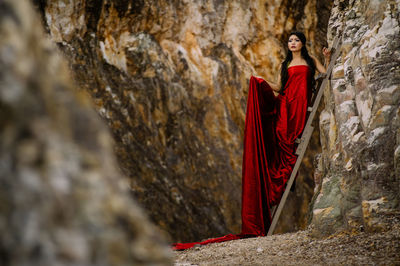 Woman standing on ladder against rock