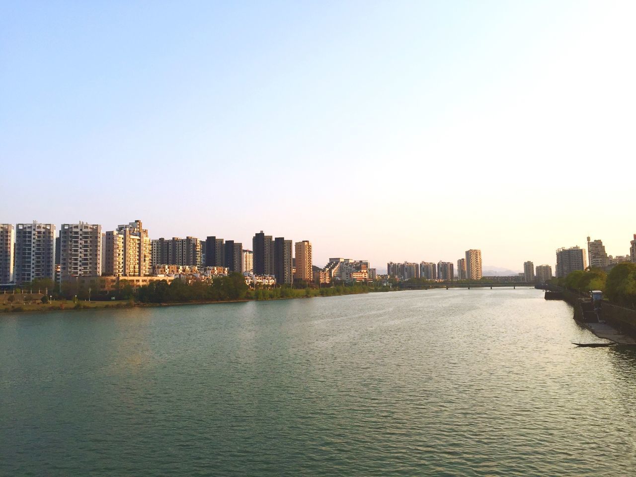building exterior, architecture, waterfront, built structure, water, city, clear sky, copy space, cityscape, river, rippled, urban skyline, skyscraper, skyline, no people, building, outdoors, sky, mid distance, sunset
