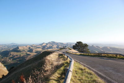 Road leading towards mountains against clear sky