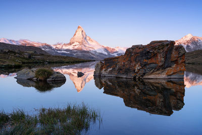 Reflection of snowcapped mountains on lake against clear sky