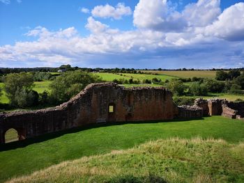 View of old ruin on field against cloudy sky