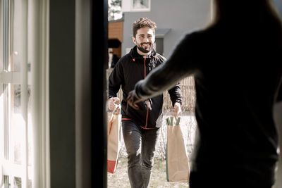 Smiling young delivery man delivering grocery to female customer at home