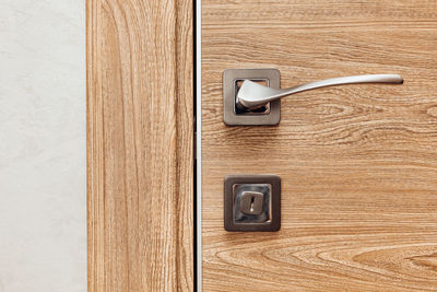 Modern metal door handle in a wooden interior door