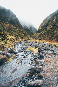 Scenic view of river by mountains against sky