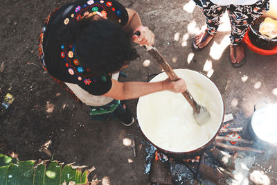 High angle view of woman stirring pot outdoors