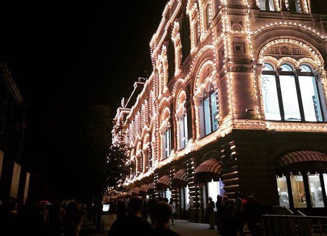 GROUP OF PEOPLE IN FRONT OF ILLUMINATED BUILDING