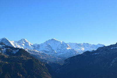 Scenic view of snowcapped mountains against clear blue sky