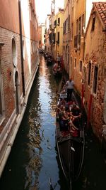 Boats moored in canal amidst buildings