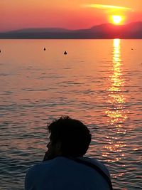 Silhouette person in sea against sky during sunset