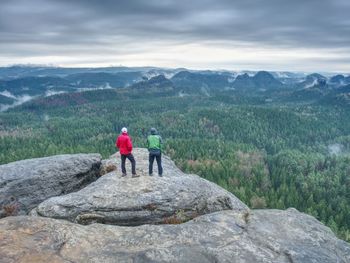 Man stay for a moment for overlooking the misty landscape below view point. trail at edge of cliff