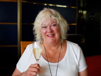 Portrait of happy senior woman holding wine at bar