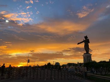 Silhouette of statue against cloudy sky during sunset