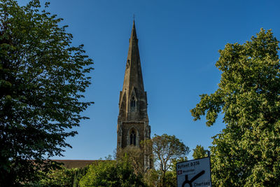 Low angle view of trees and building against sky