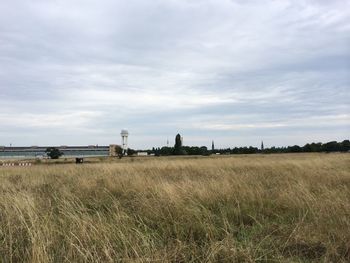 Scenic view of grassy field against cloudy sky