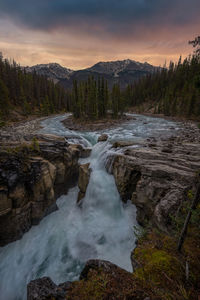 Scenic view of waterfall against sky during sunset