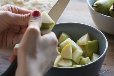 Cropped image of woman hand cutting pears with knife