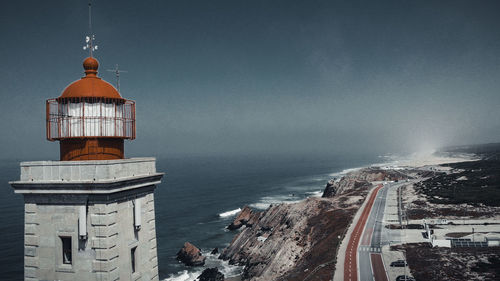 Lighthouse by sea against buildings in city