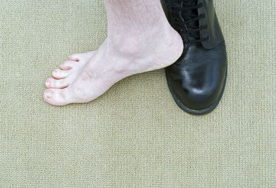 Low section of man wearing shoe in on leg on carpet