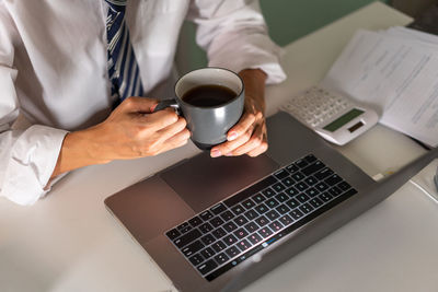 Midsection of woman using laptop on table