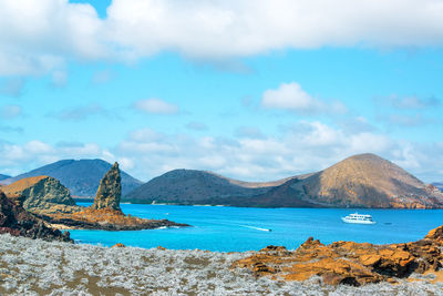 Scenic view of yacht in sea amongst mountains against cloudy sky