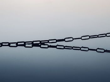 Close-up of chain on rope against sky