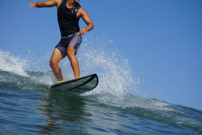 Man surfing on sea against clear sky