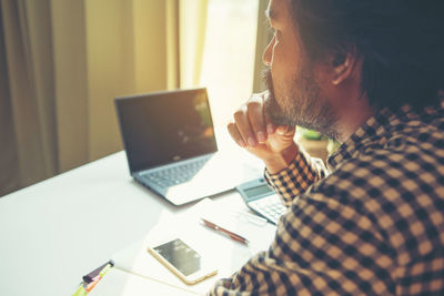 Midsection of man using mobile phone while sitting on table