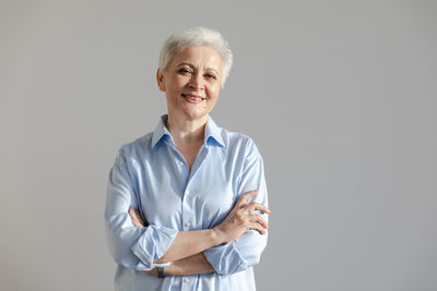 Portrait of young woman standing against white background