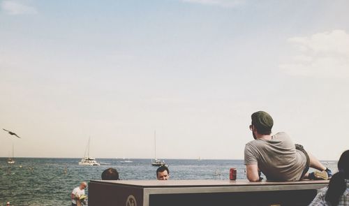 Rear view of man relaxing on table at beach