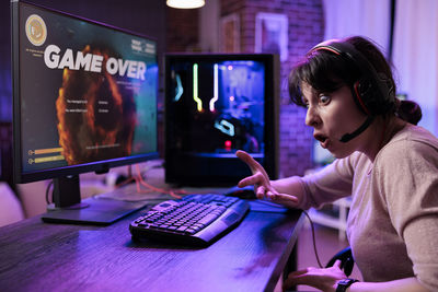 Side view of young woman using laptop at table