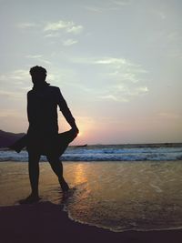 Silhouette man walking at beach against sky during sunset