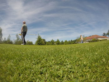 Man on golf course on field against sky