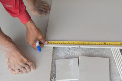 Low section of worker measuring tile