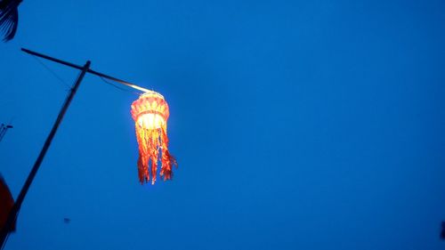 Low angle view of illuminated lantern against clear blue sky