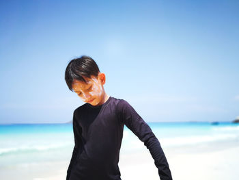 Boy standing on beach against sky