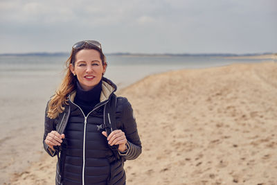 Portrait of woman standing at beach against sky