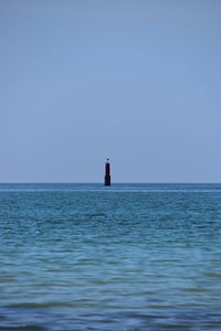 Lighthouse in sea against clear sky