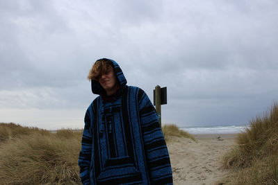 Young man standing on beach against sky