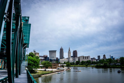 City by river and buildings against sky