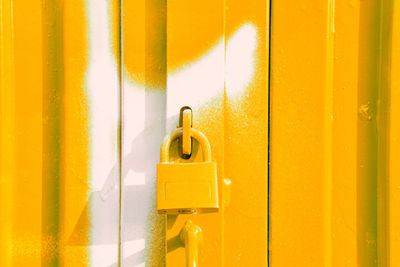 Yellow padlock on yellow and white door