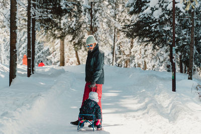 Rear view of woman walking on snow covered field